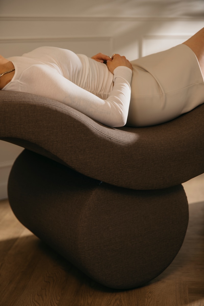 a woman laying on top of a chair on a hard wood floor